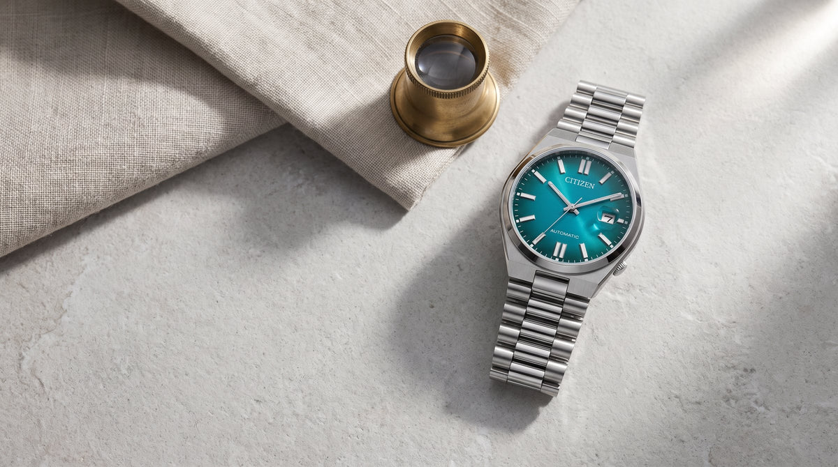 Citizen Tsuyosa automatic with a teal dial beside a watchmaker’s loupe